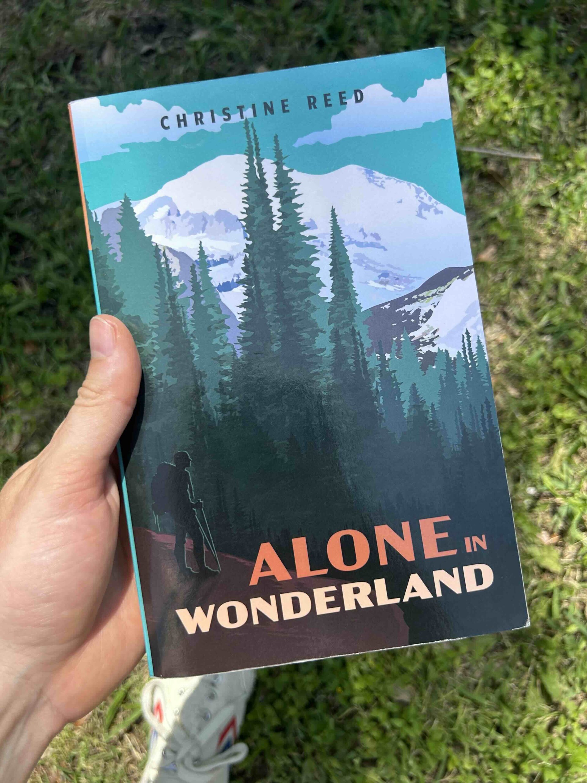 david smart holding the book alone in wonderland by christine reed